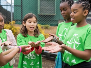 Girls on the Run participants gather with hands open to each other while they doing an activity